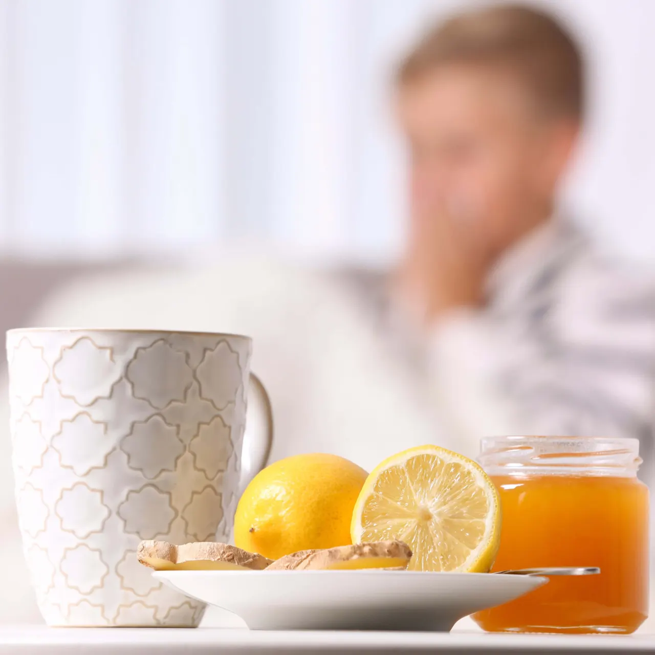 Child with a cold in the background, a mug, lemon and a jar of honey