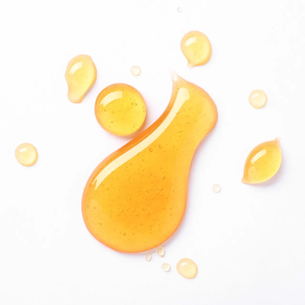 Drops of golden honey on a white background