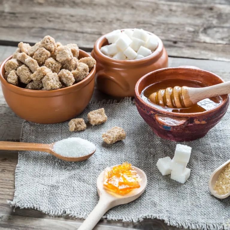 Brown sugar, white sugar and a bowl of honey compared on a table