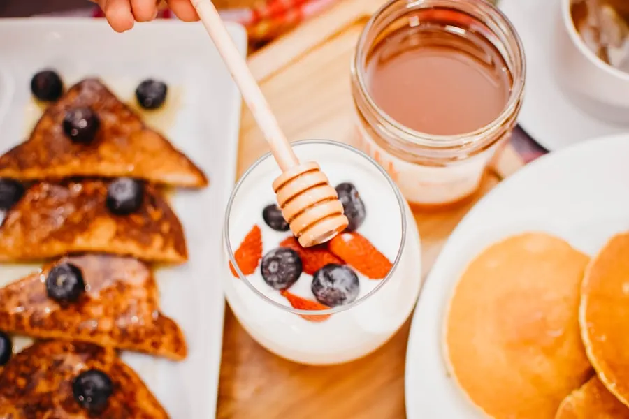 Petit-déjeuner avec miel, yaourt aux myrtilles, pain perdu et pancakes