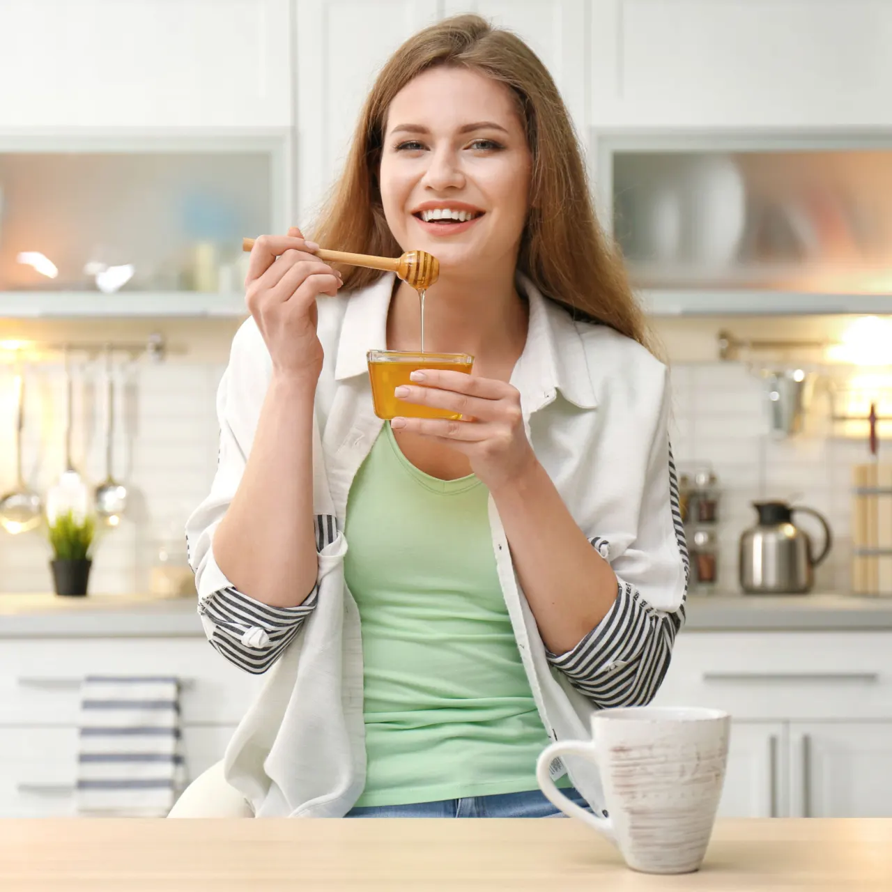 Smiling woman tasting honey in her kitchen